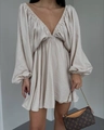 Dettaglio dell'abito beige con scollo a V, maniche a sbuffo e vita plissettata - S / Albicocca