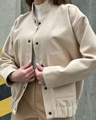 Dettaglio della giacca beige con collo alto, bottoni automatici neri e ampie tasche quadrate - S / Albicocca