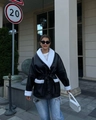 Detail of a chic black faux leather coat with white shearling trim and waist tie - S / Black