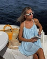 Detail of light blue summer slip dress paired with a woven straw bag on a boat - Light Blue