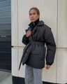 Close-up of black winter coat with lapel collar, waist belt, and horizontal stitching detail - Black