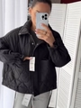 Detalle de chaqueta acolchada negra con cuello alto y bolsillos en la modelo - S / Negro