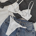 Detailaufnahme eines weißen Satin-Dessous-Sets mit Kristalldekor auf Strick und Denim - Weiß