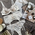 Detailed flat lay of an ivory lace three-piece lingerie set with luxury props - White