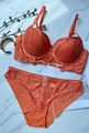 Dettaglio di un set di lingerie in pizzo arancione vivace su sfondo di marmo raffinato - Arancione / 75D