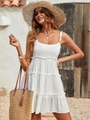 Close-up of white Swiss Dot fabric and tiered ruffle details on a summer beach dress - White
