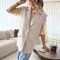 Detail view of beige sleeveless blazer vest with classic lapels and amber buttons - S / Beige