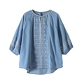Dettaglio del ricamo geometrico bianco e del bottone sulla camicia azzurra denim - M / Azzurro