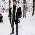 Detail van de zwarte suède herenjas met dikke beige lamswollen kraag in een sneeuwlandschap - M / Tops / Zwart