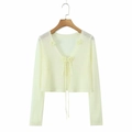 Detail view of cropped light yellow knit shrug featuring decorative 3D floral tie-up front - One Size / Yellow