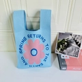Detailed knit texture of light blue floral tote with ‘AND SPRING RETURNS’ slogan - Blue Sunflower