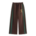 Dettaglio dei pantaloni sportivi marroni a gamba larga con strisce verdi e stampa gialla - Taglia S / Pantaloni e gonne / Marrone/Verde