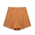 Detail view of high-waist linen shorts in caramel with pleats and side pockets - XS / Bottoms / Orange