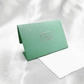 Close-up of green embossed paper envelope with white jewelry polishing cloth on silk - Blue