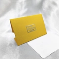 Jewelry polishing cloth with yellow textured card packaging on white satin fabric - Ginger Yellow