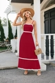 Detailed view of red sleeveless maxi dress with white wavy trim and smocked texture details - Red