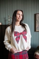 Detail van een beige sweatshirt met een grote rode tartan strik op een model - S / Wit