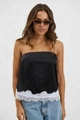 Detail eines schwarzen Satin-Bandeau-Tops mit weißer Wimpernspitze und blauen Jeans - S / Schwarz