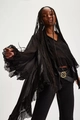 Detail of sheer black tiered blouse featuring dramatic flared cuffs and ruffled hem design - S / Black