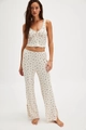 Detail of floral V-neck camisole and high waist trousers pajamas set on model - S / Top And Bottom / White
