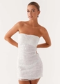 Close-up of white tube mini dress featuring floral embroidery and shimmering sequins detail - White
