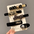 Gros plan sur un lot de 5 barrettes de luxe avec perles et strass sur carte - Style Perle Gemme Lettre Logo (24) / Combo Noir Or Blanc