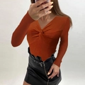 Detail of cross V-neck brick red knit sweater featuring unique front knot and ribbed texture - Caramel color
