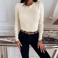 Detailed texture of off-white ribbed knit sweater featuring elegant gold button cuffs - Apricot