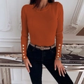 Detailed close-up of orange ribbed knit sweater sleeves with golden buttons on cuffs - Caramel color