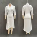 Detail view of white satin wrap dress featuring deep V-neck and asymmetrical ruffle hem - S / Dresses / White