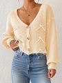 Détail d'un cardigan en maille à col en V avec boutons marbrés et nœuds blancs - S / Abricot