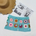 Detail of colorful hand-crocheted beach shorts with bright blue knit and 3D floral patches - Sky Blue