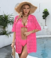 Detail of pink crochet beach cover-up with white buttons and knit texture in a resort setting - Rose Red
