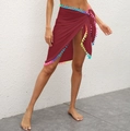 Detail of burgundy wrap beach skirt featuring colorful pom-pom fringe and side tie design - One Size / Bottoms / Wine Red