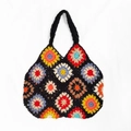 Detailed macro view of colorful granny square crochet patterns on a black tote bag - Black