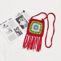 Detail view of handmade crochet bag with colorful granny square and long red fringe - Red
