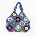 Makro-Detail einer farbenfrohen handgehäkelten Granny Square Tasche auf weißem Grund - Blau