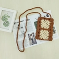 Handgewebte Boho-Handytasche mit Häkelblumenmuster auf hellem Holzhintergrund - Kaffee und Aprikose