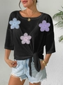 Detail of black top featuring 3D mesh floral appliques and a front tie-knot hemline - One Size / Black