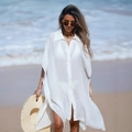 Dettaglio di un copricostume bianco semitrasparente con bottoni su una spiaggia soleggiata - Taglia unica / Bianco
