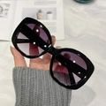 Modische Oversize-Sonnenbrille in Schwarz mit lila Verlaufsgläsern in der Hand - Schwarzer Rahmen Doppelt Graue Linse