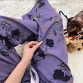 Detail of purple floral cotton pajama pants with large black flowers on soft plush rug - Purple Rhyme