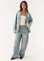 Detail of light blue washed denim jacket and high-waisted wide-leg jeans with retro zippers - Tops