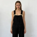 Detaillierte Nahaufnahme der schwarzen Denim-Latzhose mit Metallschnallen und Brusttaschen - S / Schwarz