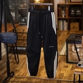 Detailaufnahme der schwarzen Jogginghose mit Seitenstreifen und Tideins Logo - M / Schwarz