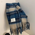 Detail eines blau karierten Strickschals mit dichten Fransen und weißem Markenetikett - Blau