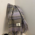 Detail eines lavendelfarbenen Karoschals mit Fransen und Markenetikett in neutralem Stil - Violett