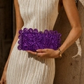 Dettaglio di una pochette da sera viola in acrilico con trama geometrica e anelli decorativi - Viola