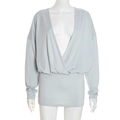 Detail view of light blue knitted dress featuring deep V-neck and draped pleats - Gray