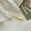 Iridescent acetate hair clip with golden metal base on a soft white fabric background - Iridescent White